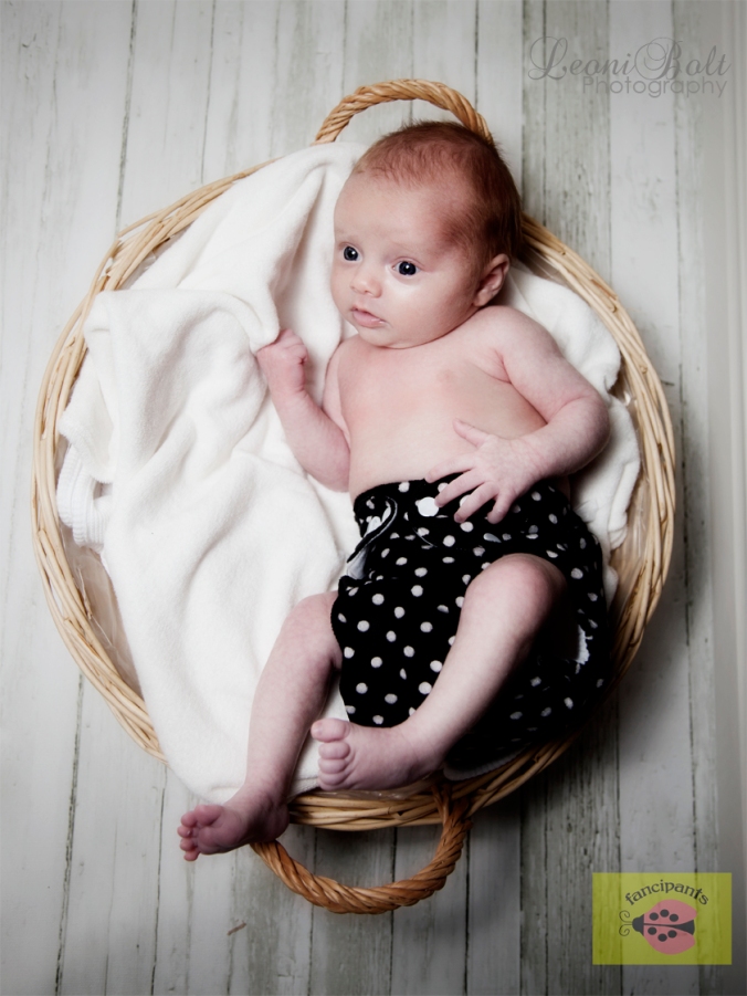 newborn in a basket on wooden floor